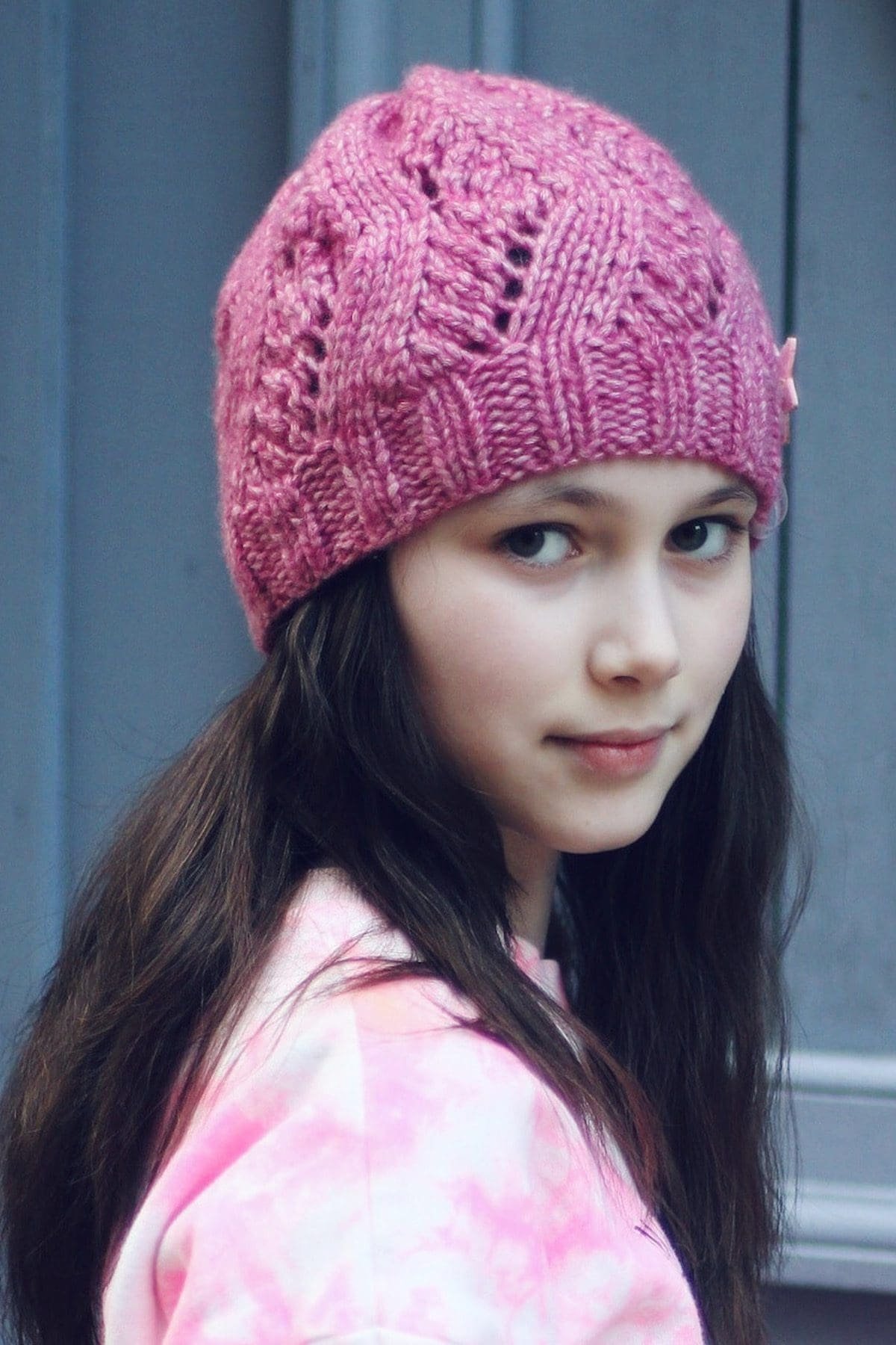 Portrait of a girl with brown hair wearing a pink knit hat. Winter fashion.