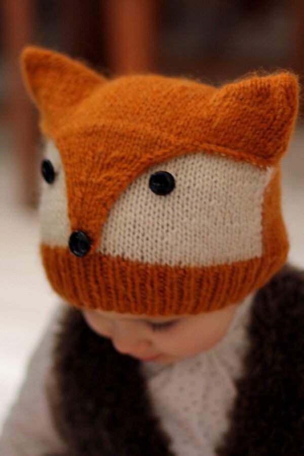 Close-up of a knitted fox hat with button eyes. Cute knitwear for kids. Winter fashion.