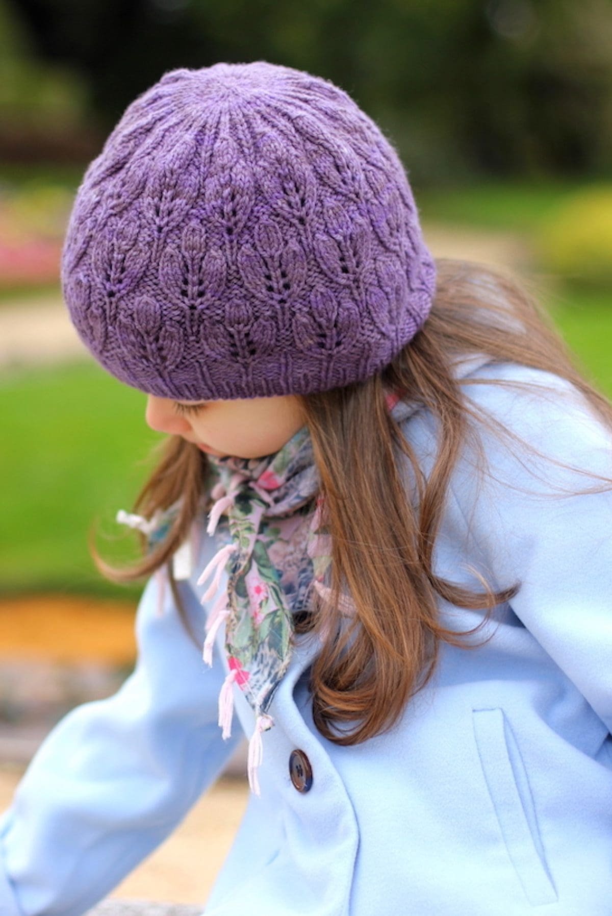 Girl in purple knit hat and floral scarf. Child fashion, winter apparel.