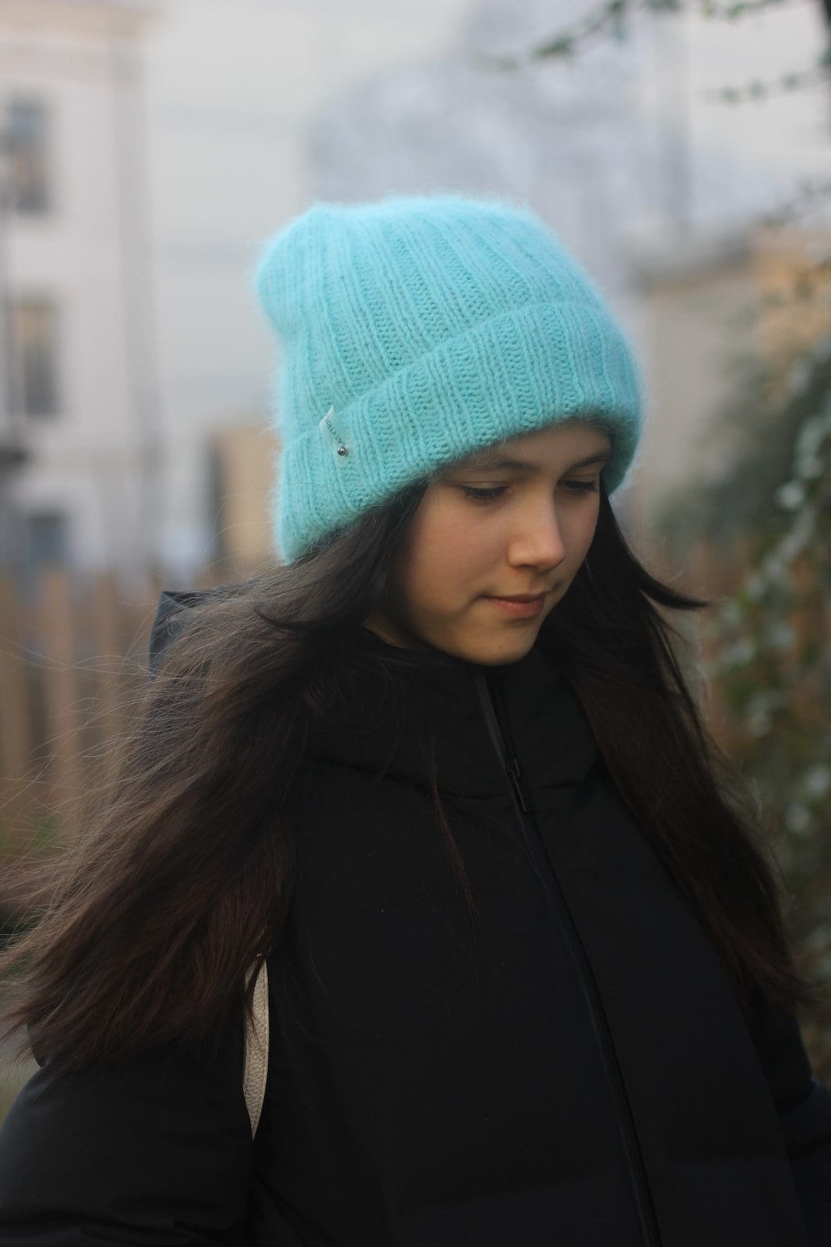 Teen girl with blue knit hat and long brown hair. Winter fashion.