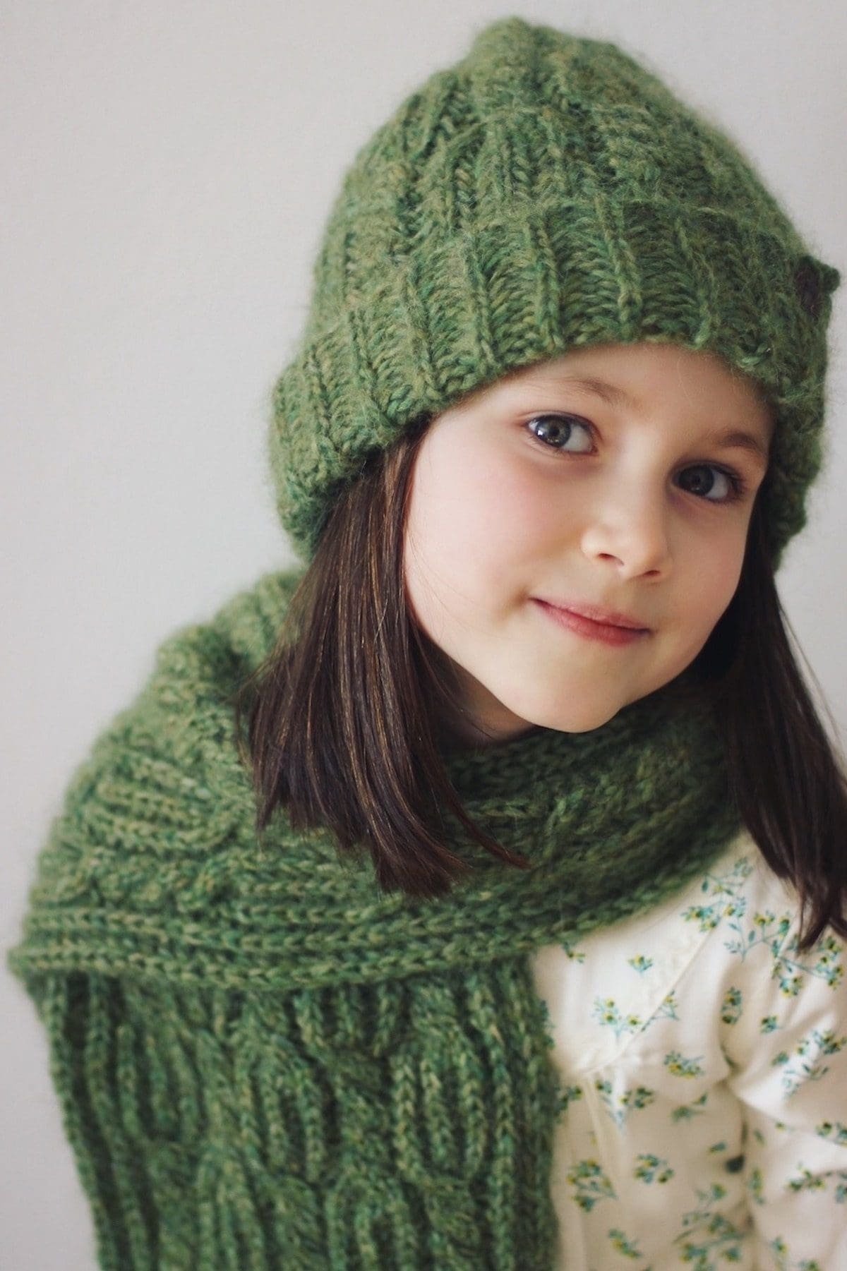 Girl in green knit hat and scarf. Winter fashion. Child portrait.