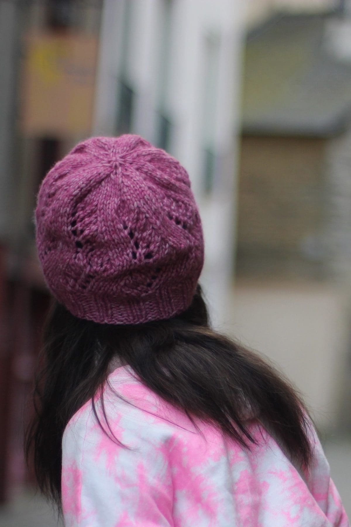 Back of head with dark hair wearing a pink knit hat. Winter fashion accessory.