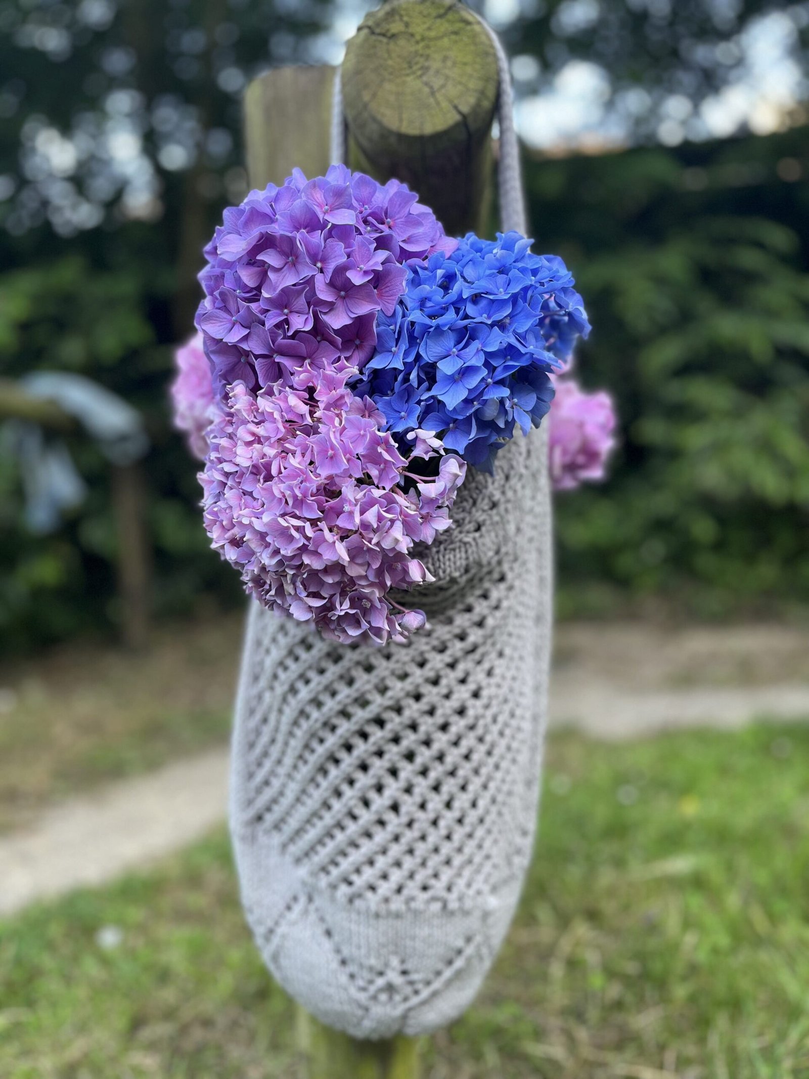 Crocheted lotus tote bag filled with blue and purple hydrangeas. Free pattern and picot hem bind-off.