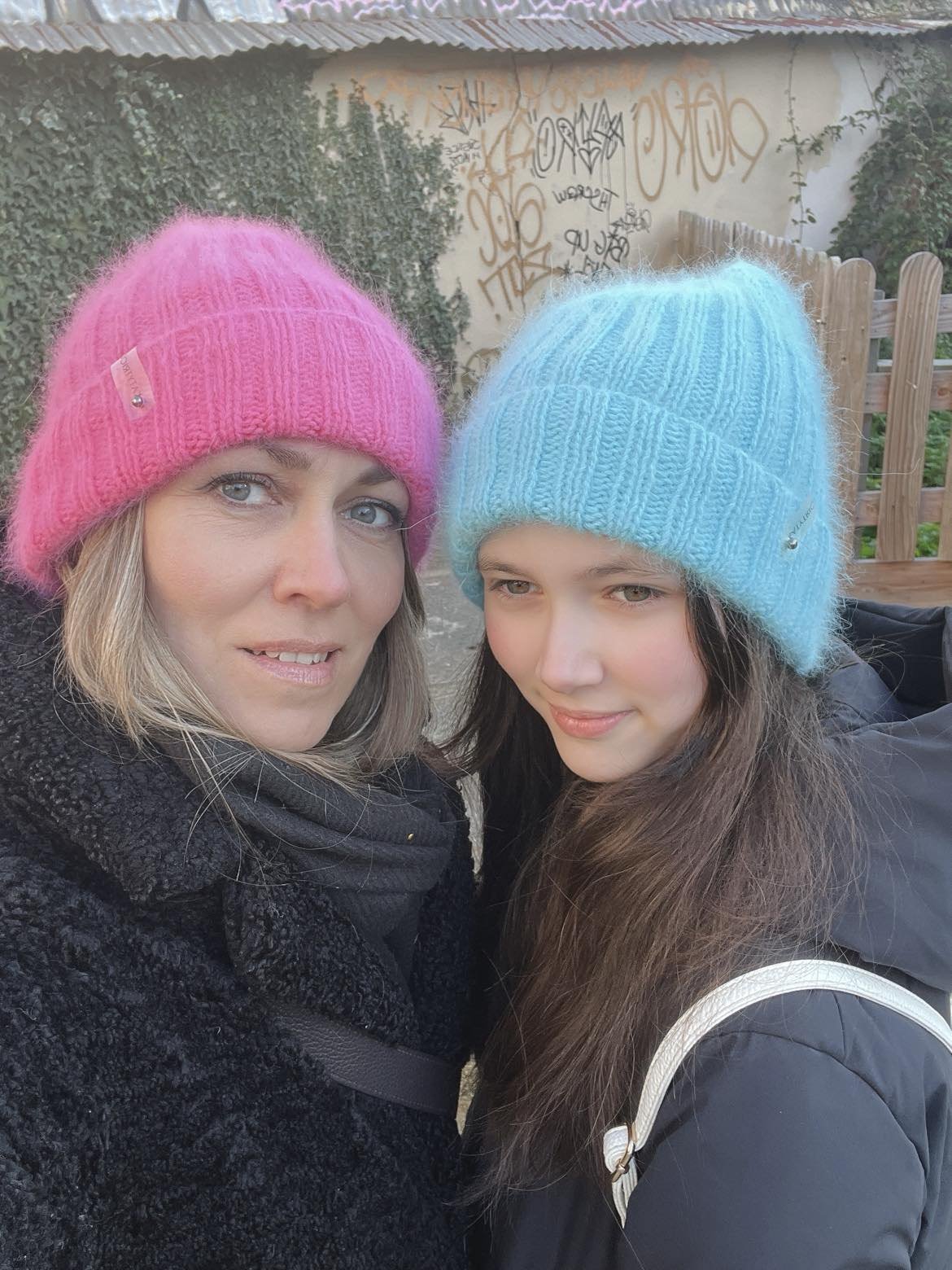 Mother and daughter selfie. Woman and girl wearing colorful winter hats. Family fashion.