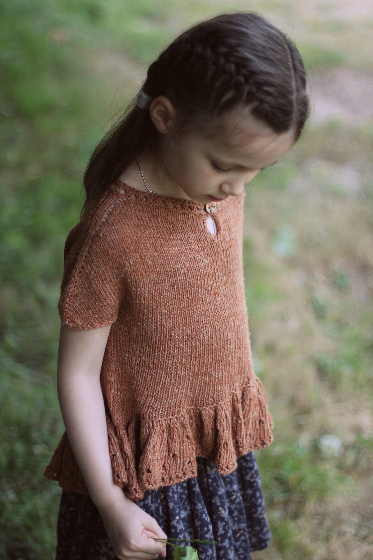 Girl wearing a brown knit dress. Handmade children's clothing. Knitwear fashion.