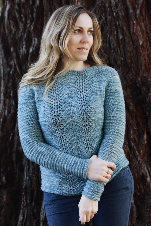 Woman wearing a blue knitted sweater. Stylish knitwear with lace pattern. Fashionable and cozy sweater.