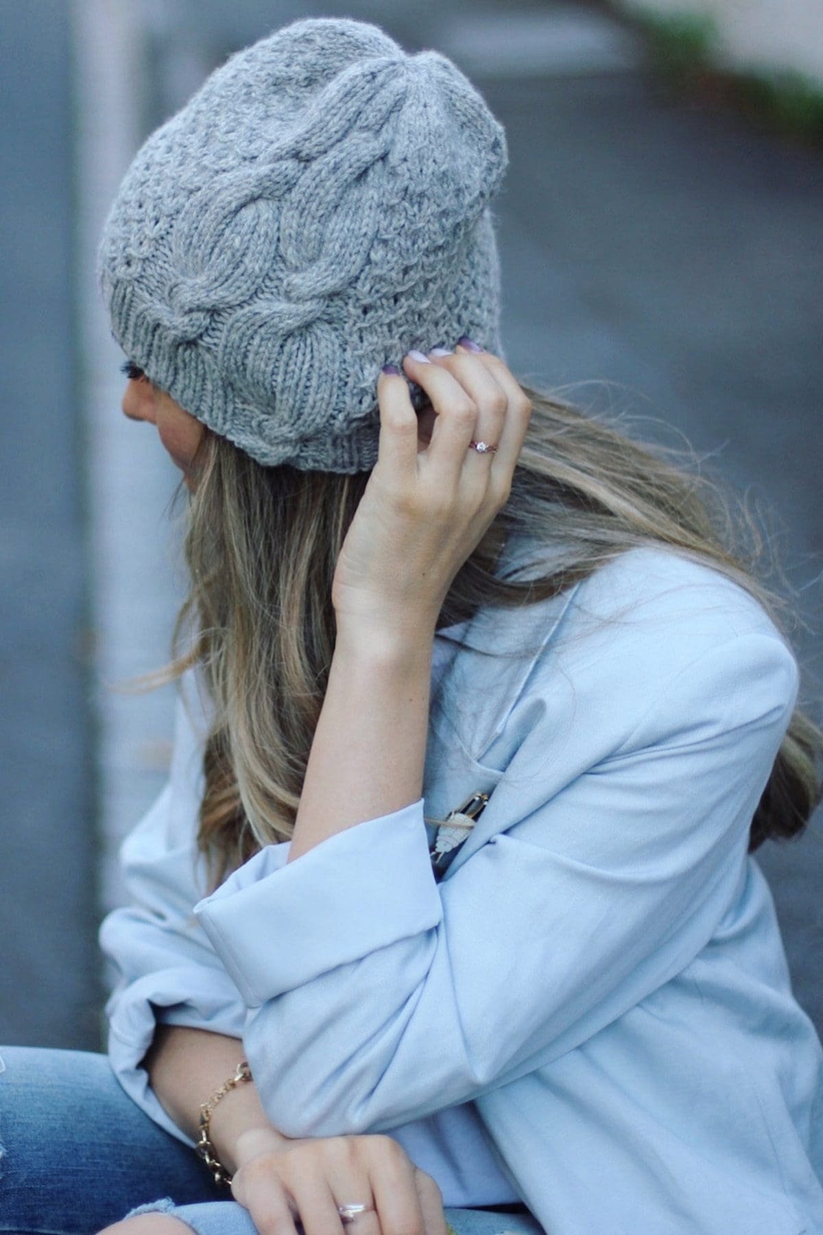 Woman wearing a gray knit hat and ring. Fashionable winter style.