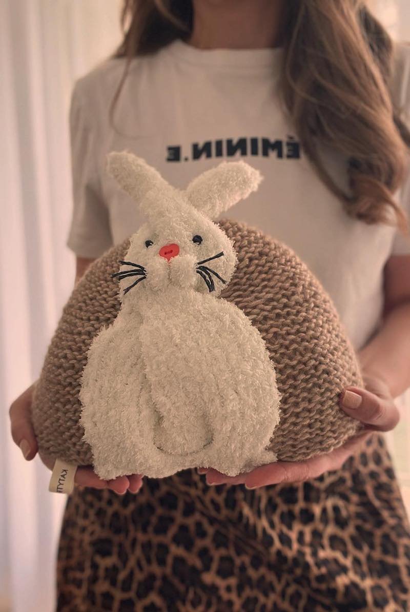 Woman holding a stuffed bunny toy. Cute plush rabbit with a brown knitted pillow. Easter gift idea.