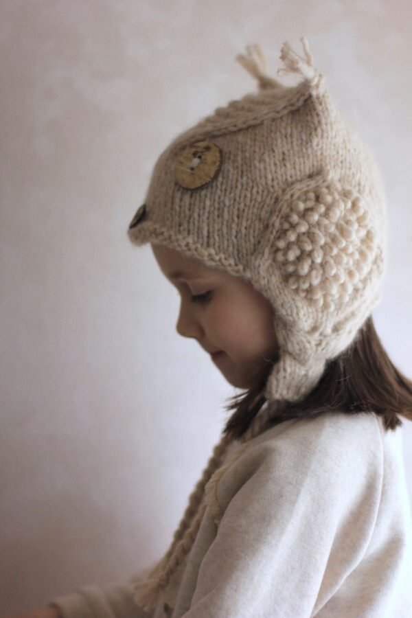 Child wearing a knit owl hat. Cute winter fashion for kids. Handmade wool beanie.