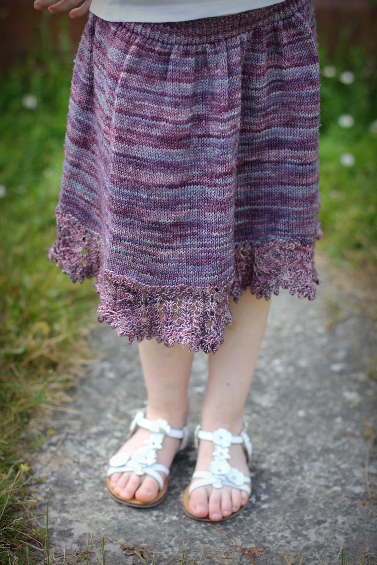 Close-up of a hand-knitted purple dress with lace hem. Knitting pattern, handmade clothing.