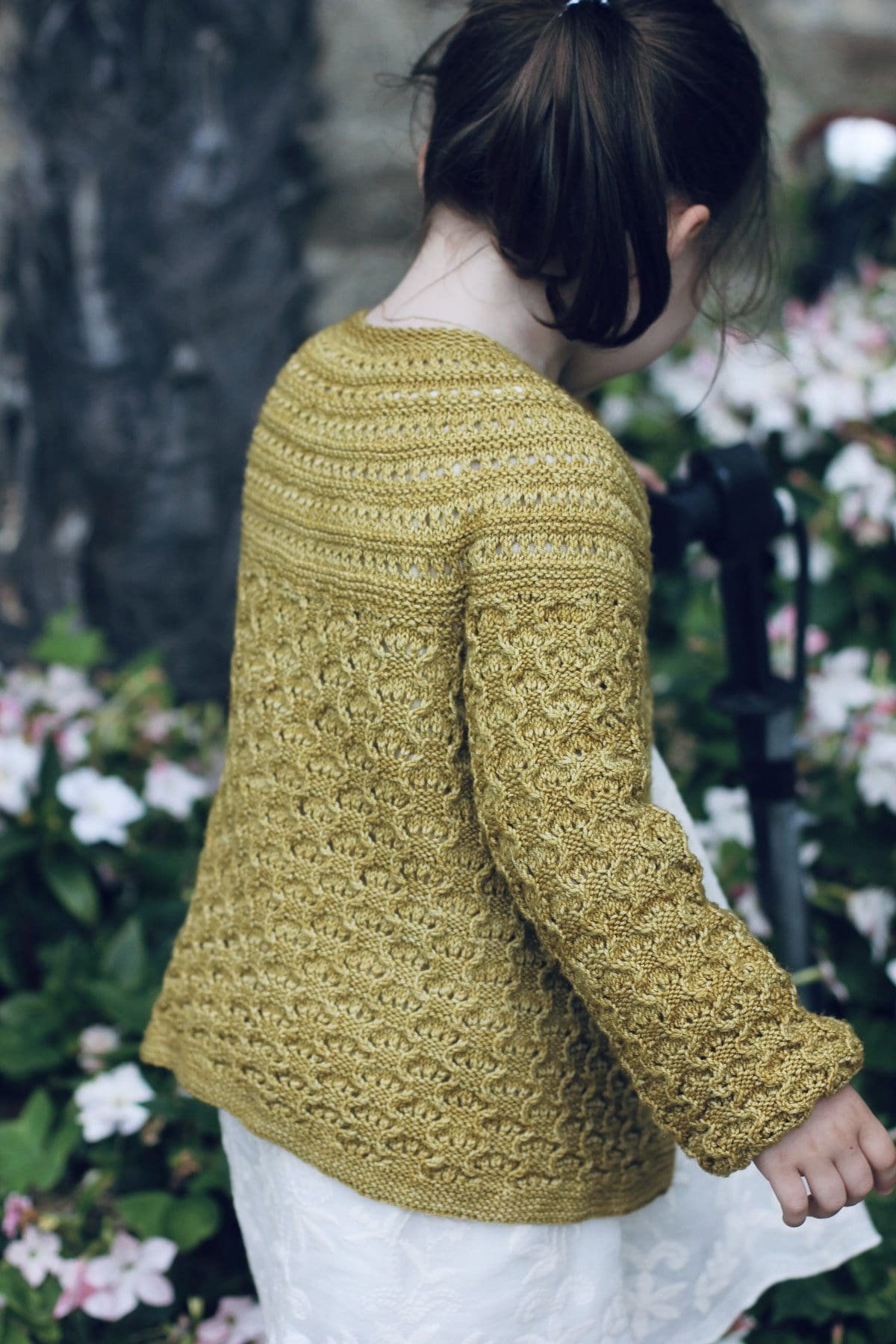 Close-up of a woman wearing a yellow knit cardigan. Stylish knitwear fashion.