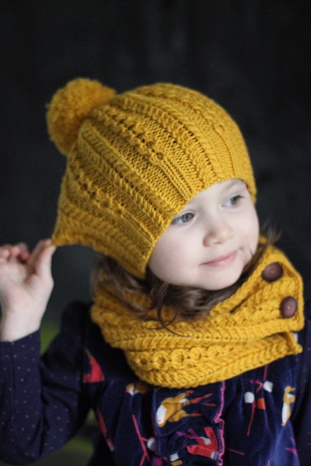 Child in mustard knit hat and scarf. Winter fashion, handmade knitwear.