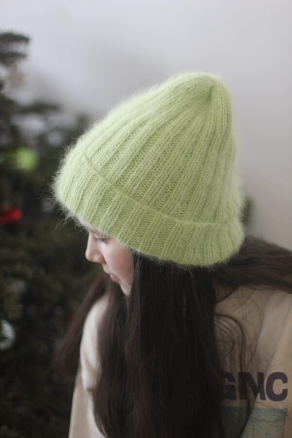Girl wearing a light green knit beanie hat. Winter fashion accessory.