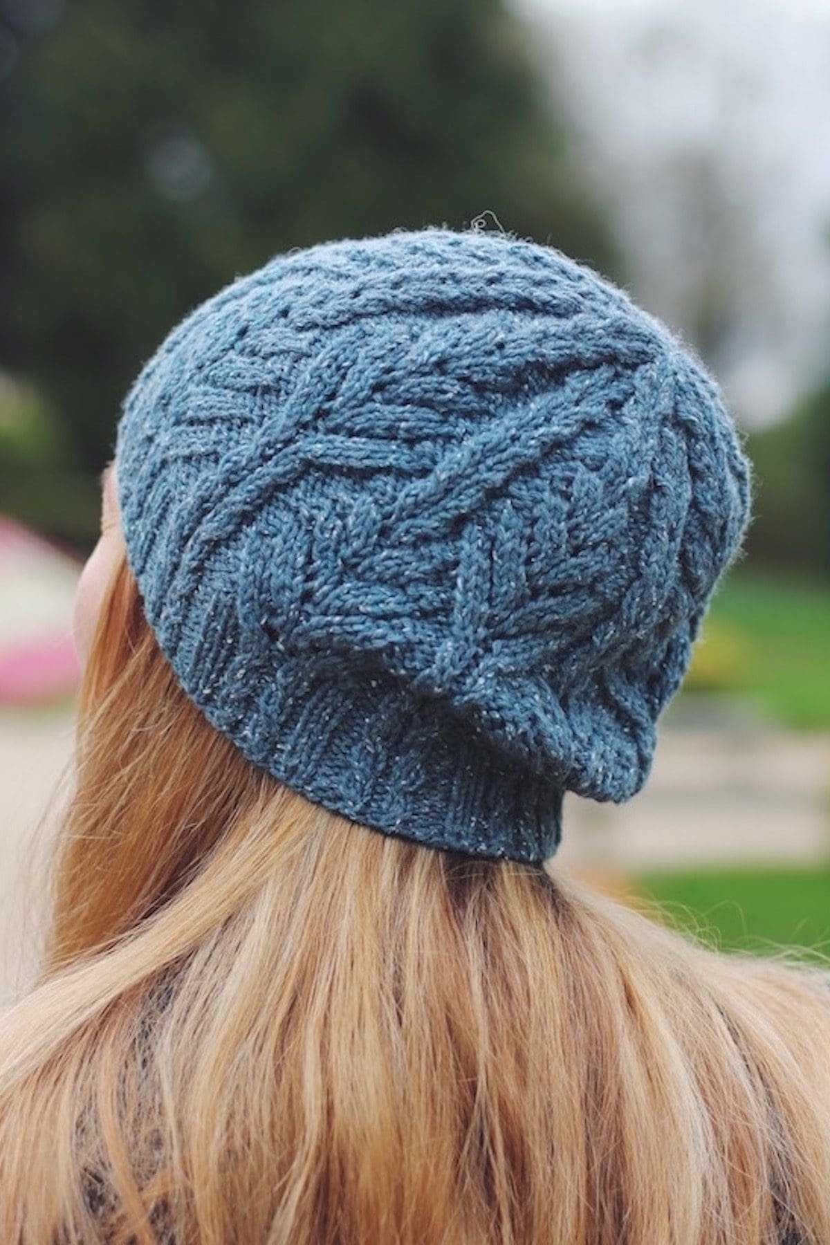 Woman wearing a blue knit hat. Cable knit pattern. Winter fashion accessory.