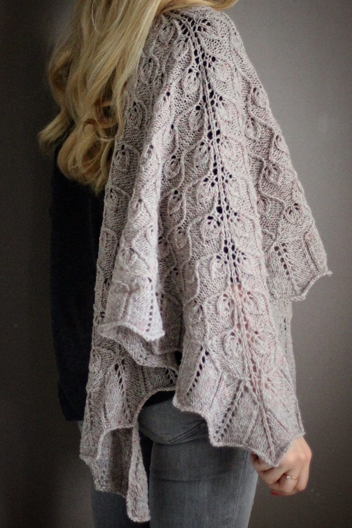Close-up of a knitted shawl with a leaf pattern. Cozy, handmade textile.