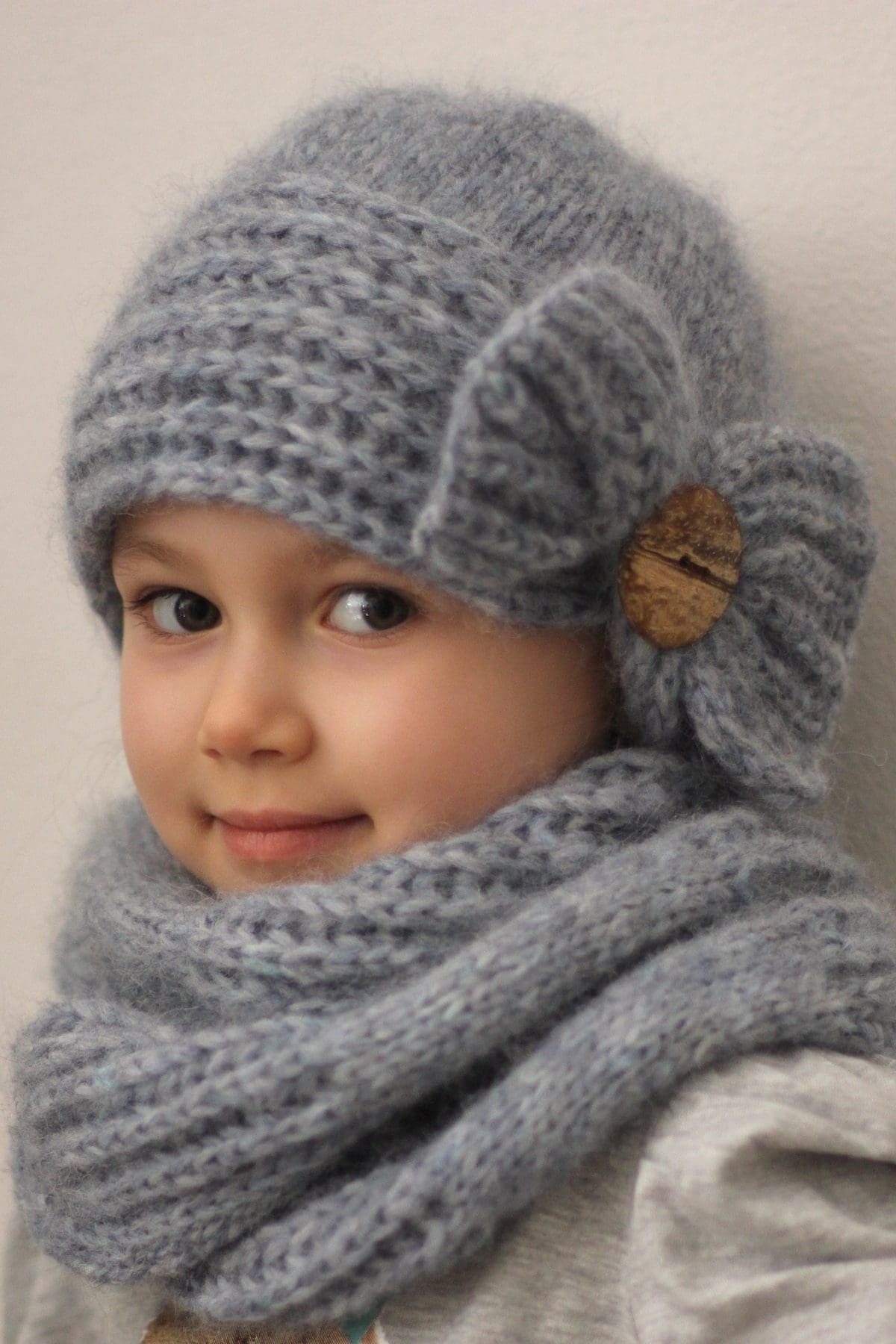 Cute girl in grey knit hat and scarf with wooden button detail. Winter fashion.