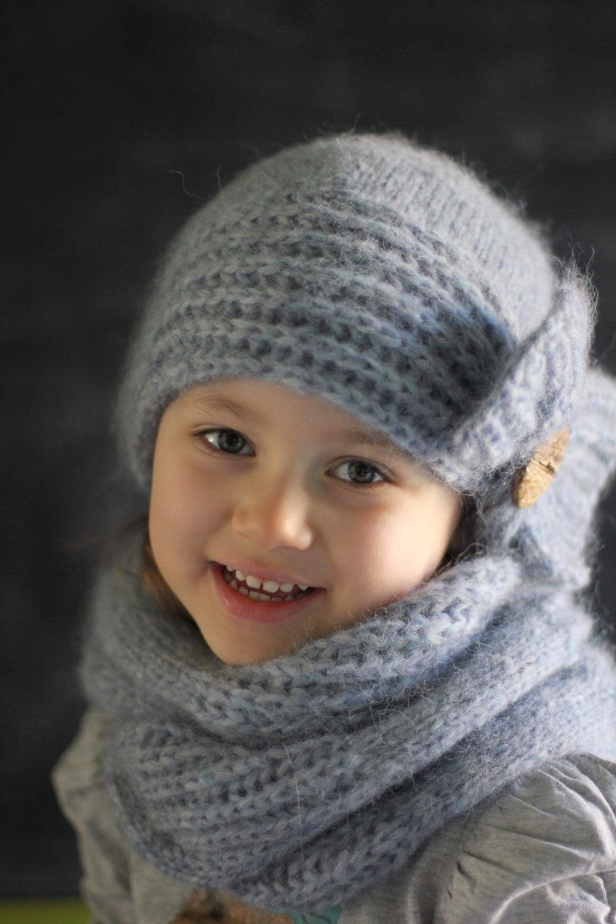 Smiling girl wearing a knitted hat and scarf. Winter fashion for kids. Coquette aesthetic.