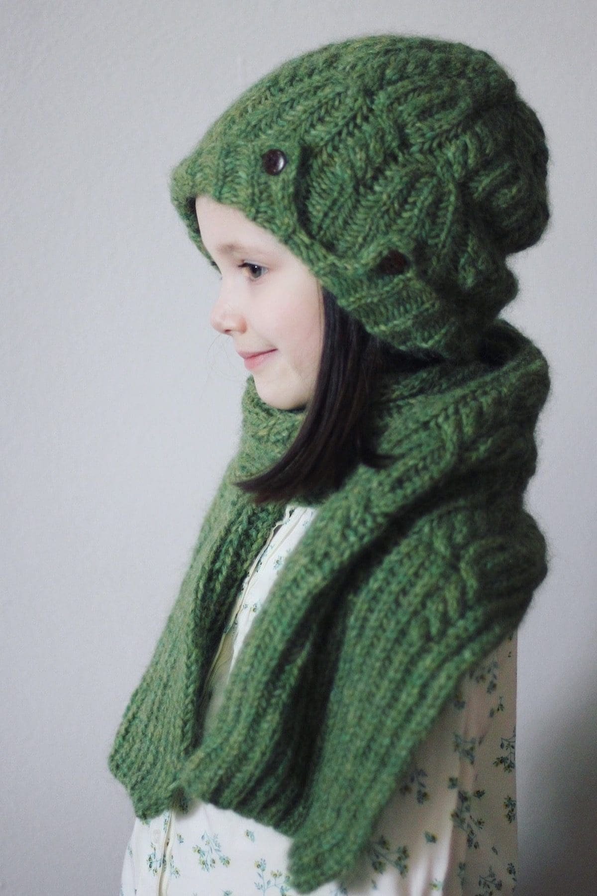 Girl wearing green knit hat and scarf. Winter fashion, handmade knitwear.