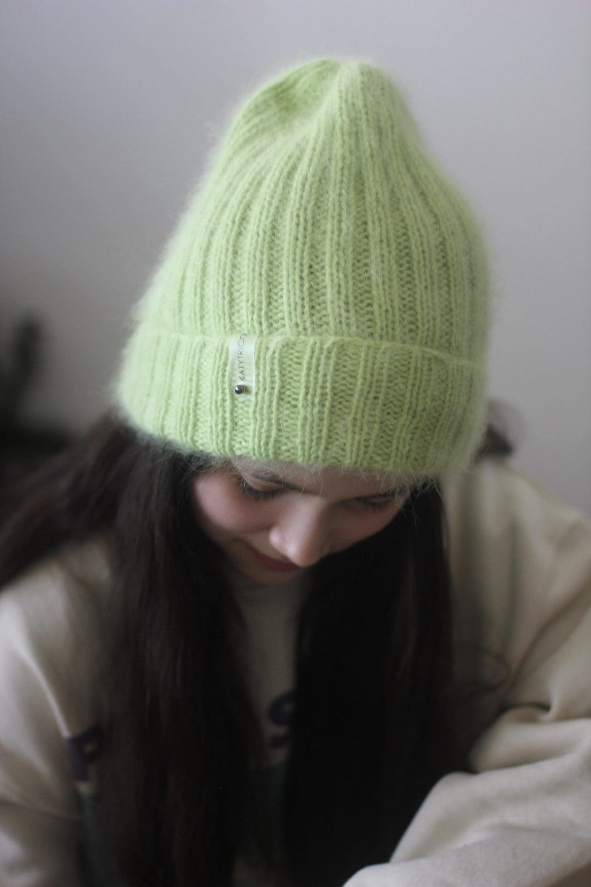 Woman wearing a neon green knit beanie. Winter fashion accessory.