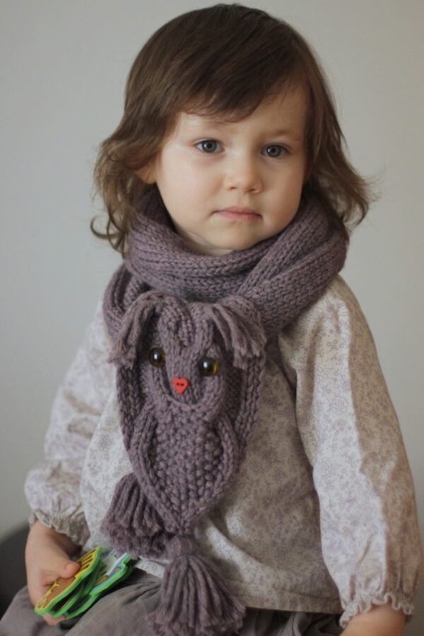 Child wearing a knit scarf with a bunny design. Cute winter fashion for kids.
