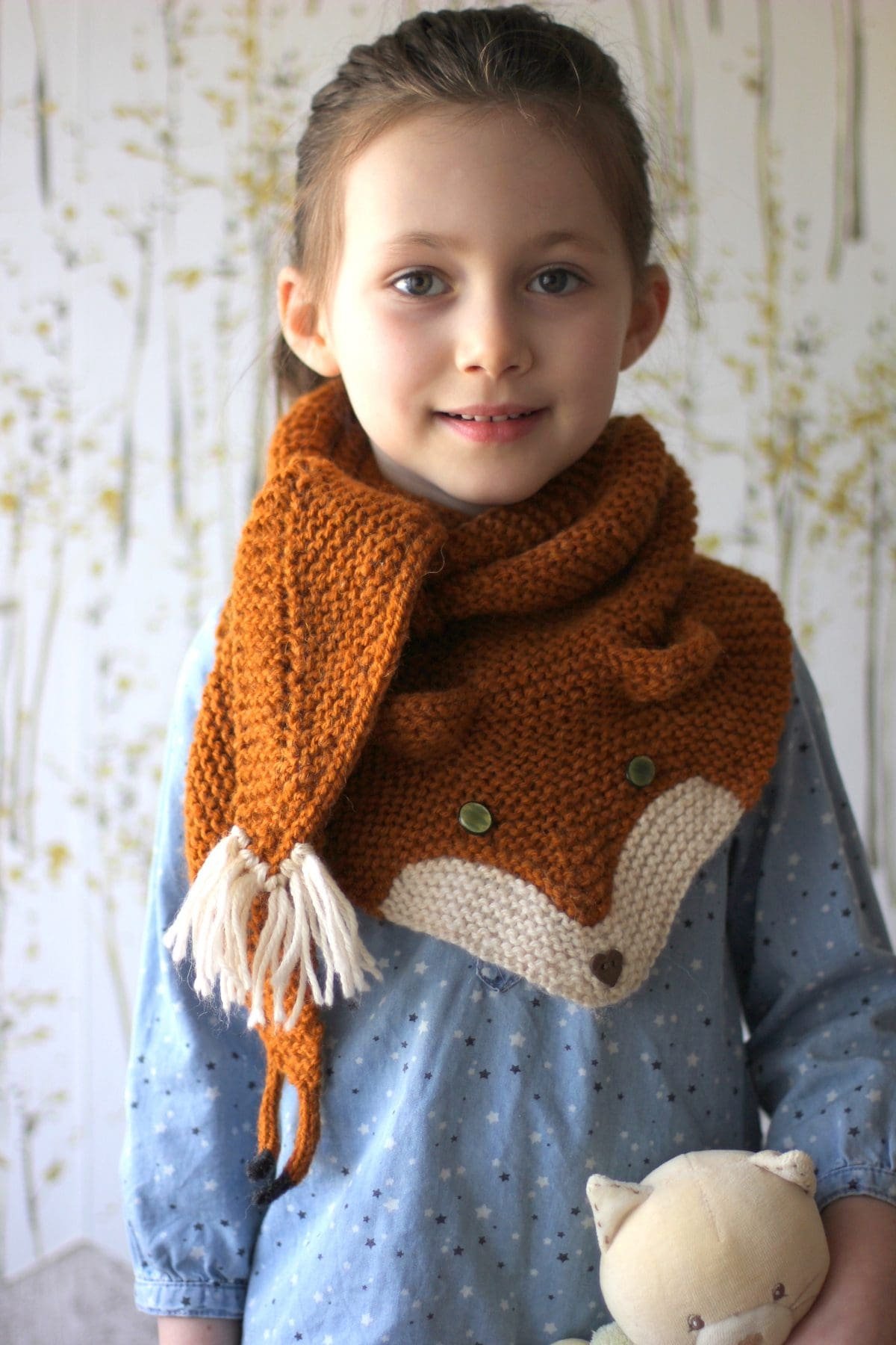 Child wearing a knitted fox scarf. Cute handmade fox neck warmer for kids. Winter fashion accessory.