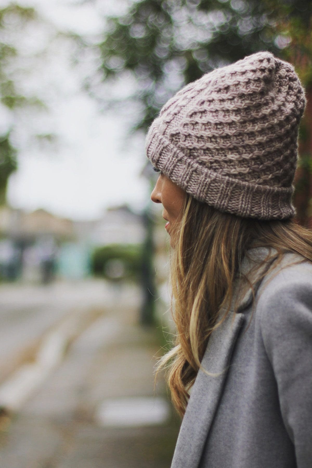 Woman in winter hat. Profile view of a blonde woman wearing a knitted hat and coat. Winter fashion.