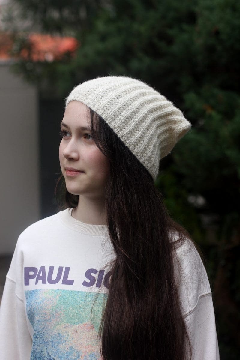 Woman wearing a knitted beanie hat. Winter fashion. Cream-colored knit hat.