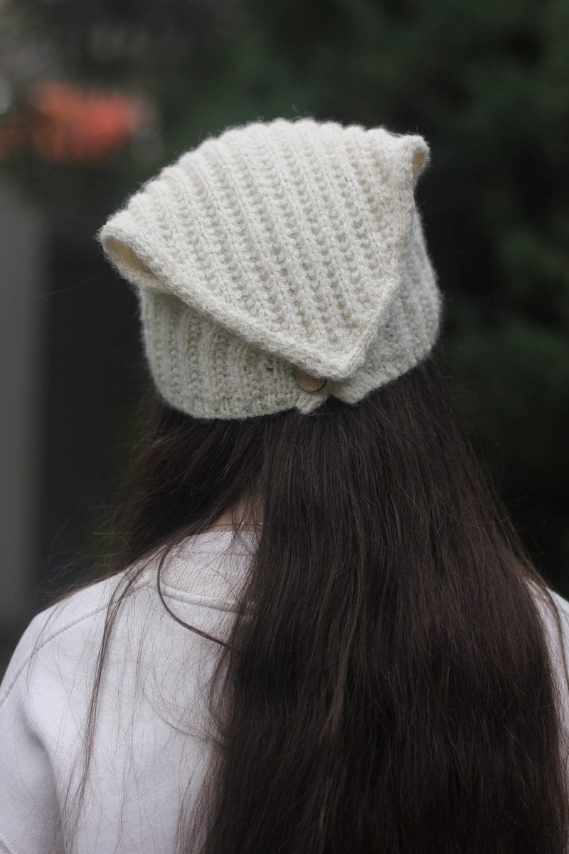 Woman wearing a cream knit hat. Winter fashion, knitted headwear.