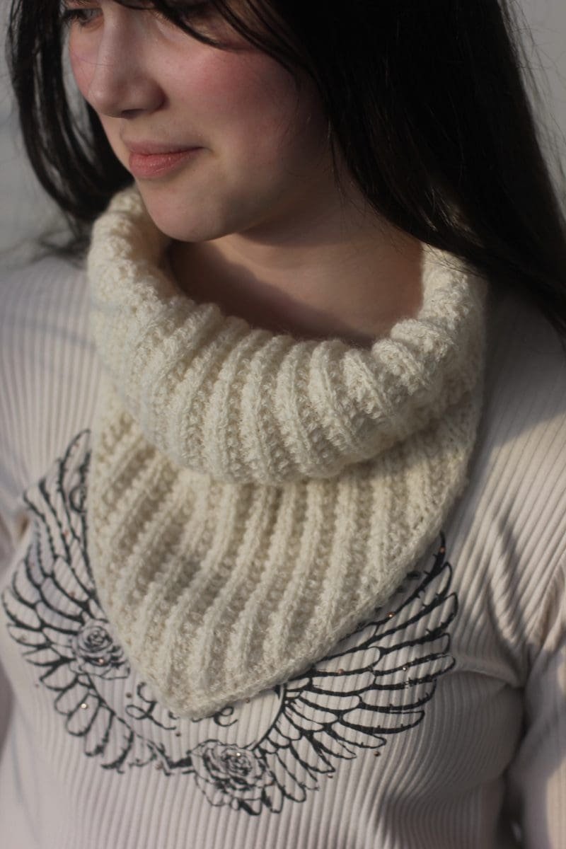 Woman wearing a handmade, white, knitted cowl neck warmer. Winter fashion accessory.