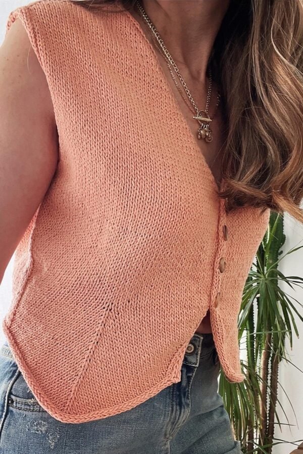 Cathy Vest: Close-up of a peach knit vest with button detail. Stylish and comfortable knitwear.