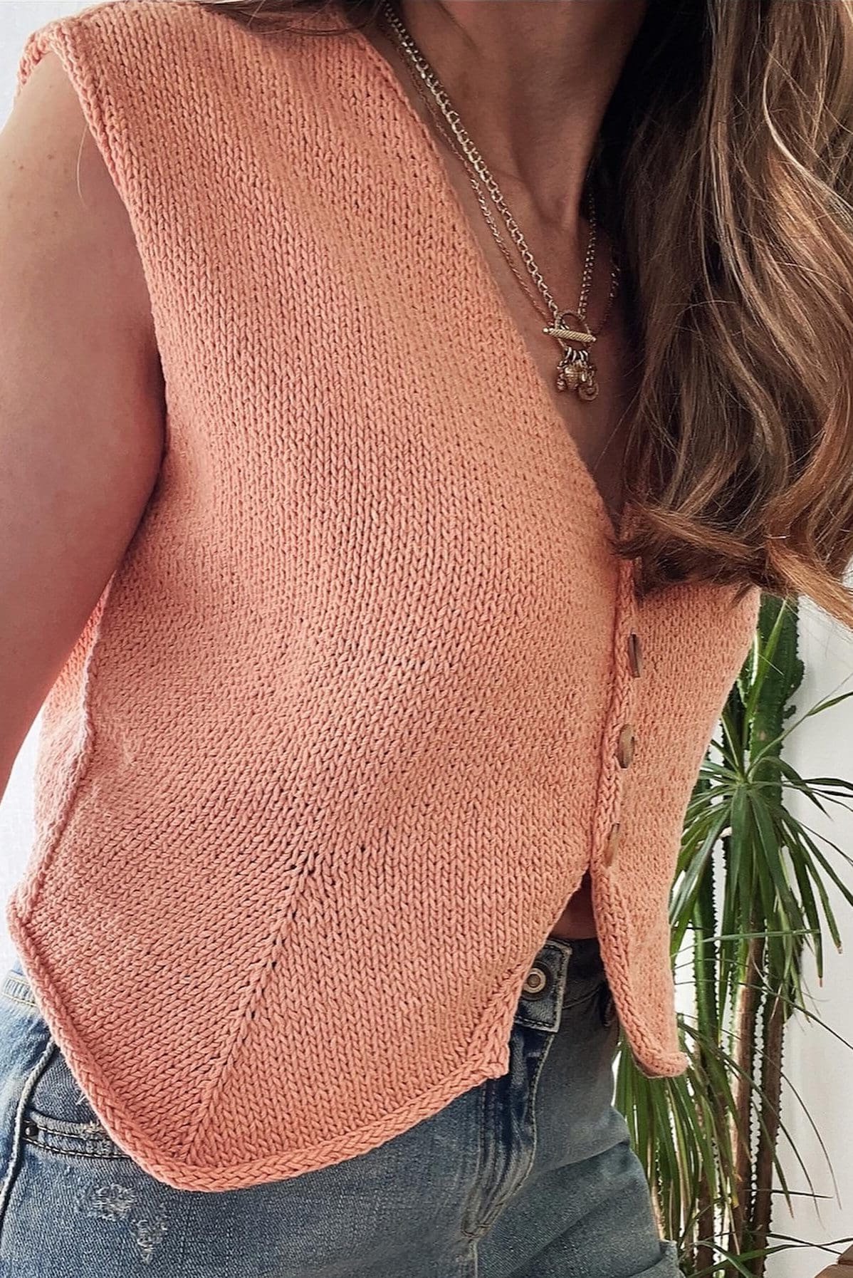 Cathy Vest: Close-up of a peach knit vest with button detail. Stylish and comfortable knitwear.