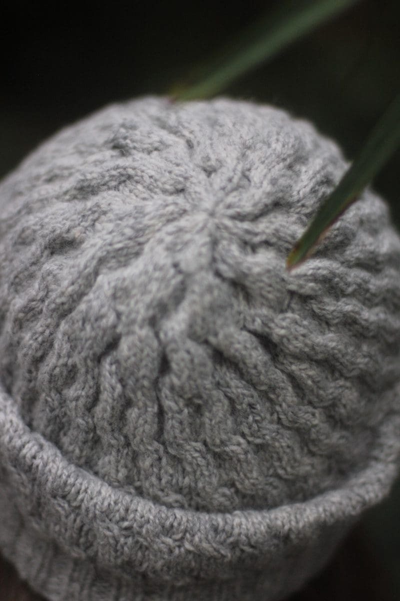 Close-up of a soft swell beanie. Gray knit hat with a ribbed texture. Winter headwear.